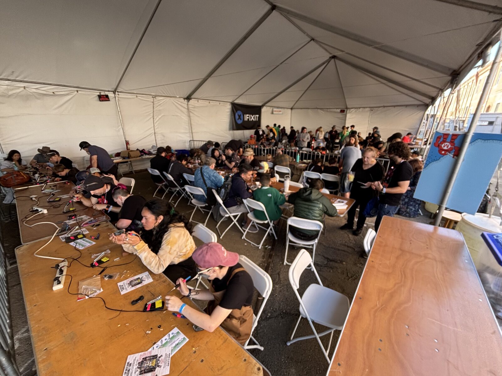 Mass soldering workshop under a tent, dozens of participants