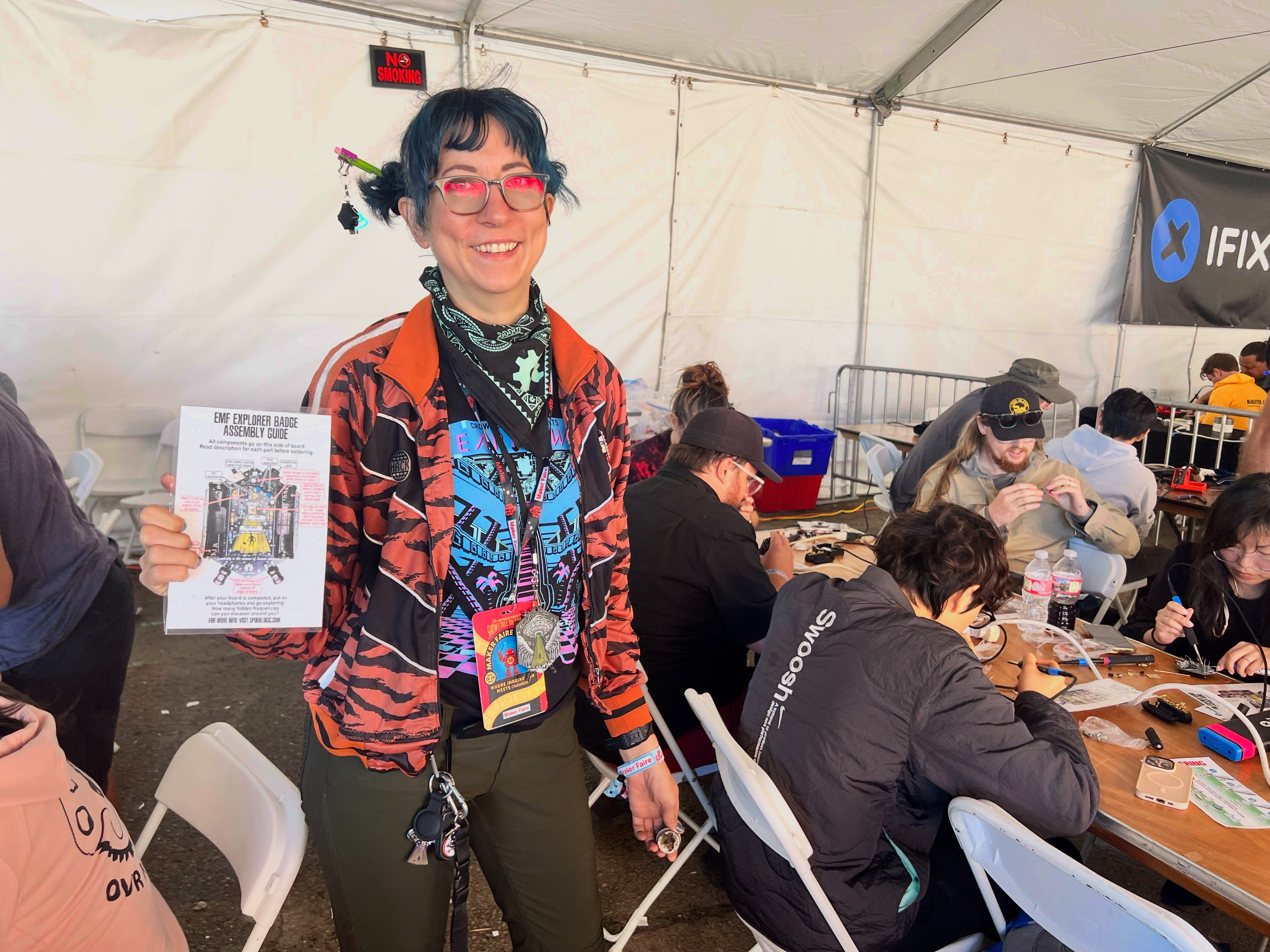 Workshop instructor holding the EMF Explorer assembly guide at Maker Faire